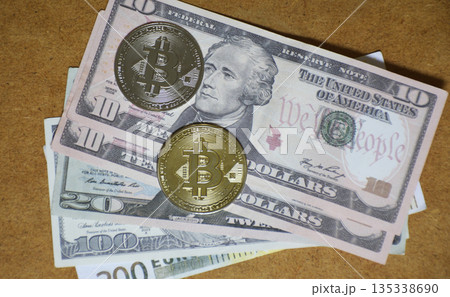 Two Bitcoin coins and dollar bills on a wooden background 135338690