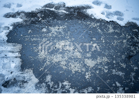 Deicing chemicals on snowy street in winter. Slippery road sprinkled with technical salt 135338981