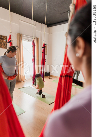 Women practicing aerial vinyasa yoga in studio Women practicing aerial vinyasa yoga in studio 135339169