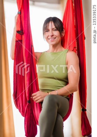 Woman smiling relaxing in aerial yoga hammock 135339175