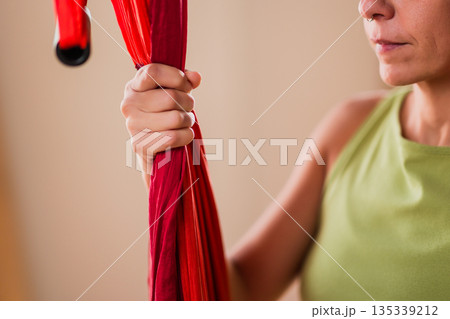 Woman holding red aerial yoga hammock fabric Woman holding red aerial yoga hammock fabric 135339212