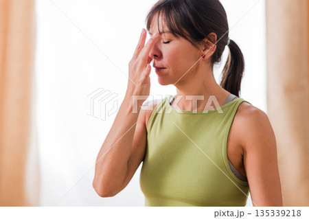 Woman practicing nadi shodhana pranayama alternate nostril breathing Woman practicing nadi shodhana pranayama alternate nostril breathing 135339218