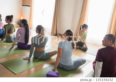 Diverse group practicing yoga twist pose in studio Diverse group practicing yoga twist pose in studio 135339232