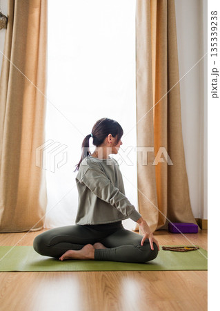 Hispanic woman practicing yoga seated spinal twist Hispanic woman practicing yoga seated spinal twist 135339238