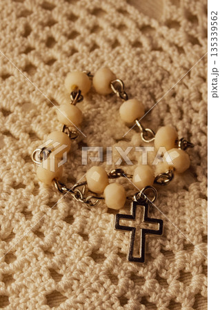 Rosary beads and cross resting on a crocheted lace background Rosary beads and cross resting on a crocheted lace background 135339562