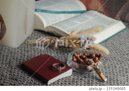 Open Bible, wooden rosary with crucifix, devotional book and cross ring on a knitted blanket Open Bible, wooden rosary with crucifix, devotional book and cross ring on a knitted blanket 135340085