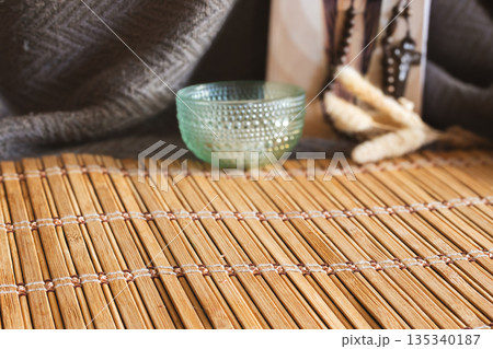 Bamboo mat with a textured glass bowl and dried plants creating a spiritual altar Bamboo mat with a textured glass bowl and dried plants creating a spiritual altar 135340187