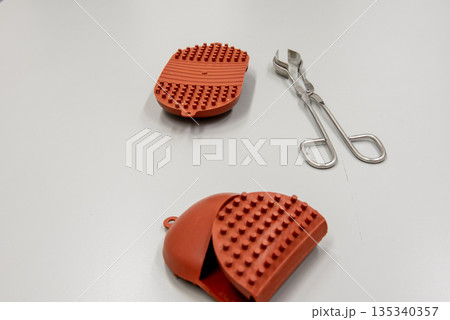 silicone hot pads and forceps on gray table in laboratory. silicone hot pads and forceps on gray table in laboratory. 135340357