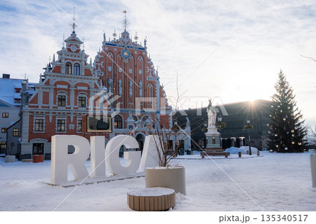 Town Hall Square in Riga shows the House of the Blackheads, the Roland statue, a big RIGA sign, and a decorated tree in snow, late afternoon in cool light. 135340517