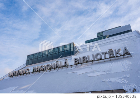 Low angle winter view of the National Library of Latvia in Riga shows the Castle of Light facade with snow, the sign Latvijas Nacionala Biblioteka, and footprints on the slope. Low angle winter view of the National Library of Latvia in Riga shows the Castle of Light facade with snow, the sign Latvijas Nacionala Biblioteka, and footprints on the slope. 135340538