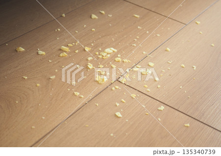 Food crumbs scattered on wooden floor in a kitchen area 135340739