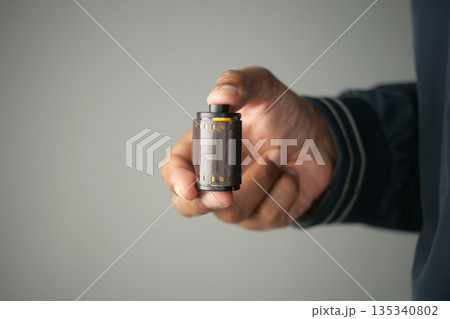 Holding a roll of film in a hand indoors 135340802