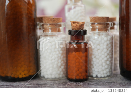 Bottles filled with small round items on a table 135340834