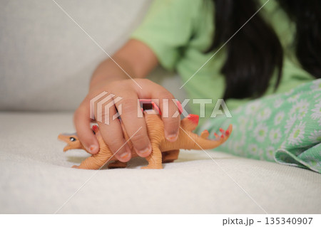 Child plays with dinosaur toy on a couch in living room 135340907