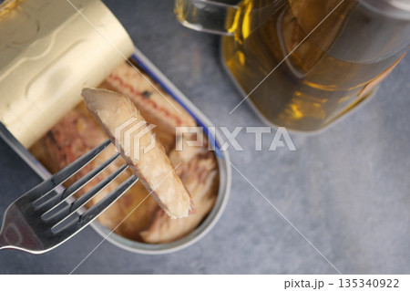Eating canned fish with a fork and a drink nearby Eating canned fish with a fork and a drink nearby 135340922