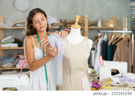 Seamstress shaping dress on mannequin in tailoring studio 135341239