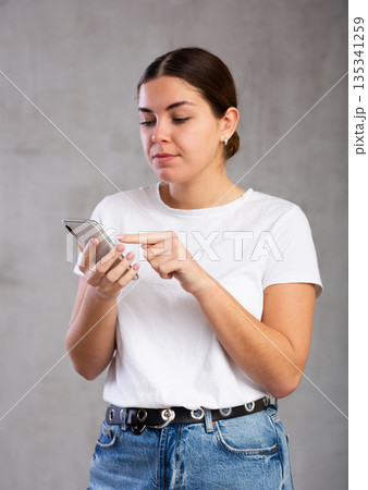 Calm young woman looking interestedly at mobile 135341259