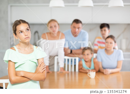 Angry female child turned away from parents and sisters and ignores relatives. 135341274