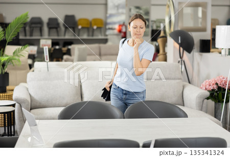 Satisfied woman chooses new modern table in furniture store Satisfied woman chooses new modern table in furniture store 135341324