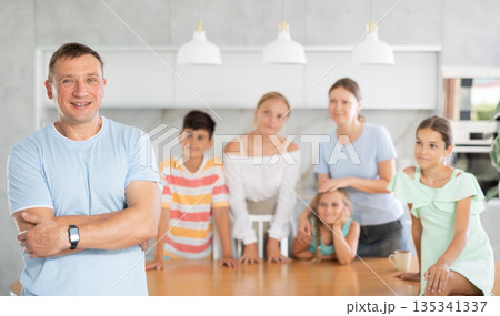 Smiling dad poses in cozy kitchen, large family with four children and wife are standing behind 135341337