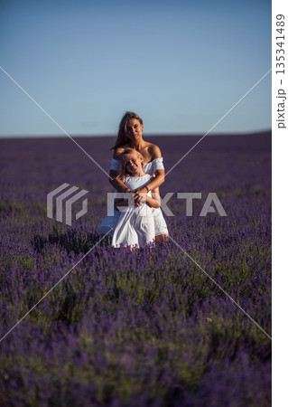 Mother daughter hugging happily in vast purple lavender field outdoors 135341489