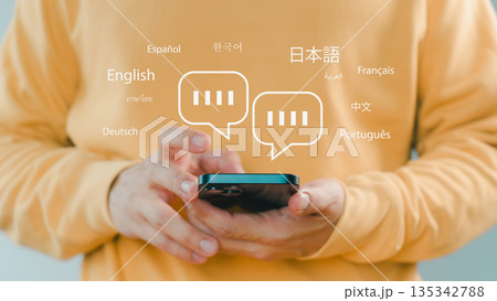 Person using smartphone with multilingual chat icons, representing global communication, language translation, online messaging, and international connection through modern mobile technology. Person using smartphone with multilingual chat icons, representing global communication, language translation, online messaging, and international connection through modern mobile technology. 135342788