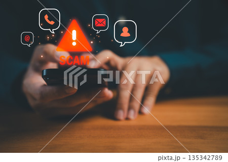 Close-up of hands holding smartphone with glowing scam warning icons, symbolizing online fraud, phishing, and cybersecurity awareness against fake messages, phone scams, and digital identity theft. 135342789