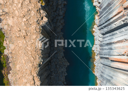 Studlagil Canyon in Iceland features dramatic basalt columns and a vibrant turquoise river. The rugged terrain and light create striking contrasts. Studlagil Canyon in Iceland features dramatic basalt columns and a vibrant turquoise river. The rugged terrain and light create striking contrasts. 135343625