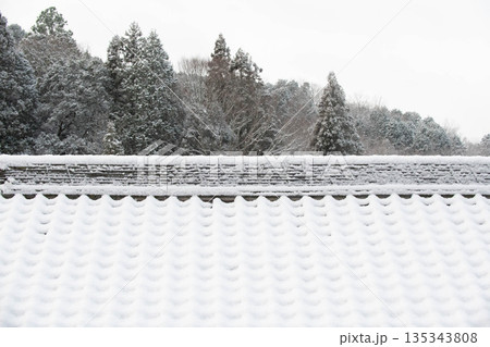 古民家の瓦屋根に積もった雪 135343808