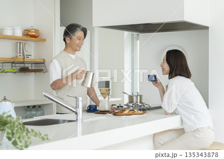 キッチンでコーヒーを楽しむ50代の夫婦 キッチンでコーヒーを楽しむ50代の夫婦 135343878