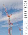 3基の赤白に塗装された建設用クレーンと青空 135343905