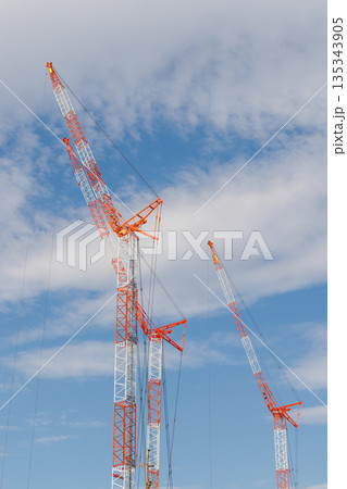 3基の赤白に塗装された建設用クレーンと青空 3基の赤白に塗装された建設用クレーンと青空 135343905