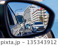 都会の渋滞と街並みを映し出す走行中の車のサイドミラー 135343912