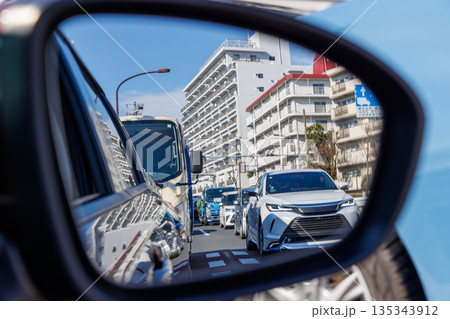 都会の渋滞と街並みを映し出す走行中の車のサイドミラー 135343912