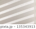 窓から差し込む柔らかい陽光とブラインドの影が作る壁の背景素材 135343913