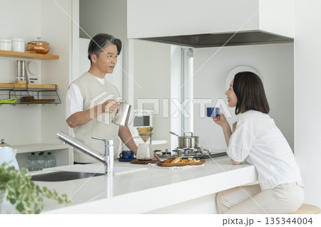 キッチンでコーヒーを楽しむ50代の夫婦 キッチンでコーヒーを楽しむ50代の夫婦 135344004