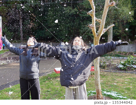 冬の朝の積雪の公園で楽しく雪合戦で遊んでいる子供姉妹の姿 冬の朝の積雪の公園で楽しく雪合戦で遊んでいる子供姉妹の姿 135344042