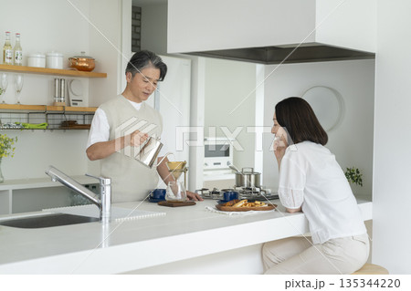 キッチンでコーヒーを楽しむ50代の夫婦 キッチンでコーヒーを楽しむ50代の夫婦 135344220