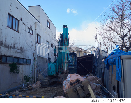 冬の街の住宅街の家を解体する重機とゴミの様子	 135344764