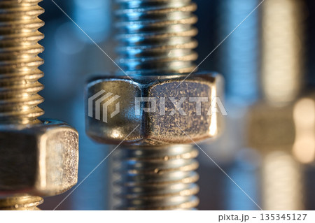 Selective focus on heavy-duty steel nuts and bolts with warm and cool light contrast 135345127