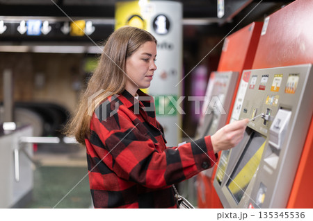 Girl buys travel ticket from machine at subway stop Girl buys travel ticket from machine at subway stop 135345536