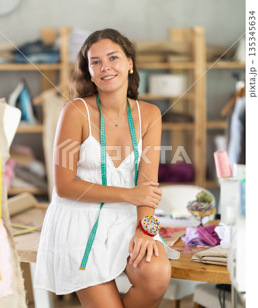 Woman dressmaker in dress invites to order clothes Woman dressmaker in dress invites to order clothes 135345634