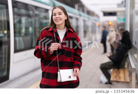 Woman standing at a tram stop 135345636