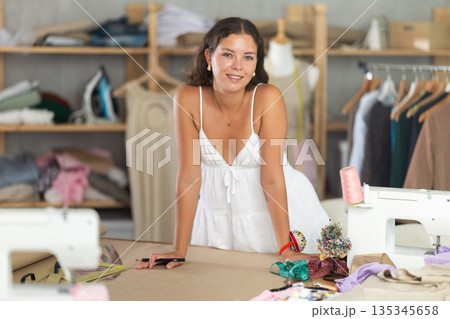 young dressmaker draws a sketch with the help of curved rulers 135345658