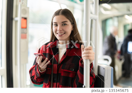 Girl is standing with phone in tram car, getting to work 135345675
