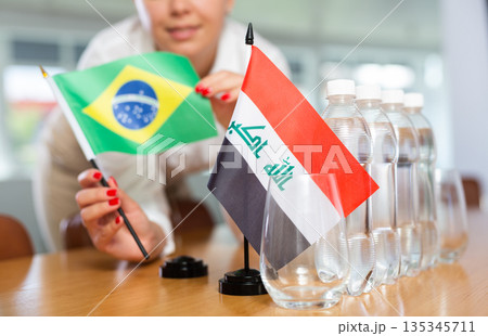 Female secretary places flags of the Iraq and Brazil flag on the table before negotiations of top political figures Female secretary places flags of the Iraq and Brazil flag on the table before negotiations of top political figures 135345711