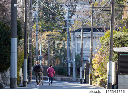 冬の朝の住宅街の道で歩く二人のシニア夫婦の姿 冬の朝の住宅街の道で歩く二人のシニア夫婦の姿 135345736