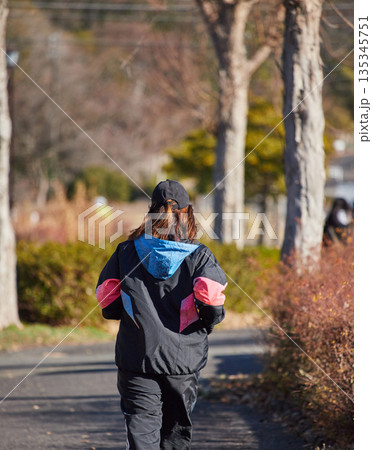 冬の朝の公園でランニングする女性の姿 冬の朝の公園でランニングする女性の姿 135345751
