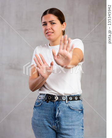 Irritated young woman posing crossly against gray background Irritated young woman posing crossly against gray background 135345942