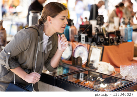 Young woman chooses vintage cutlery at flea market 135346027